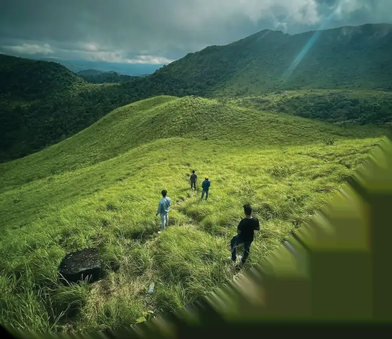 Trekkers walking through green meadows in Kakkadampoyil