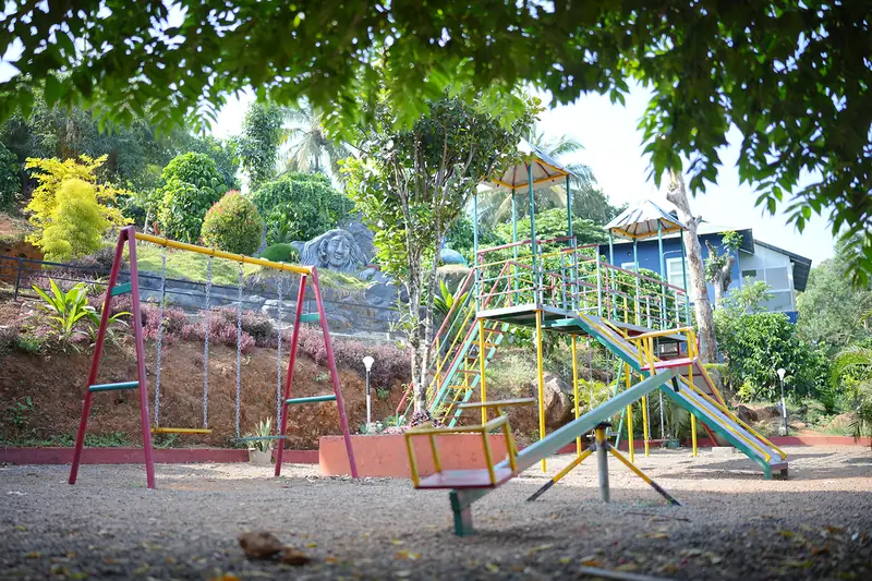 Kids play area with swings, slide and seesaw at Purayil Resort