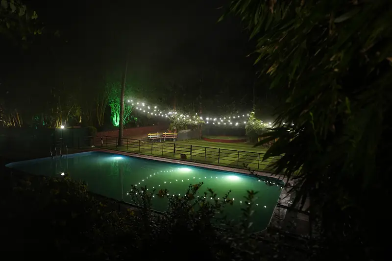 Swimming pool and string lights at night at Purayil Resort Kakkadampoyil